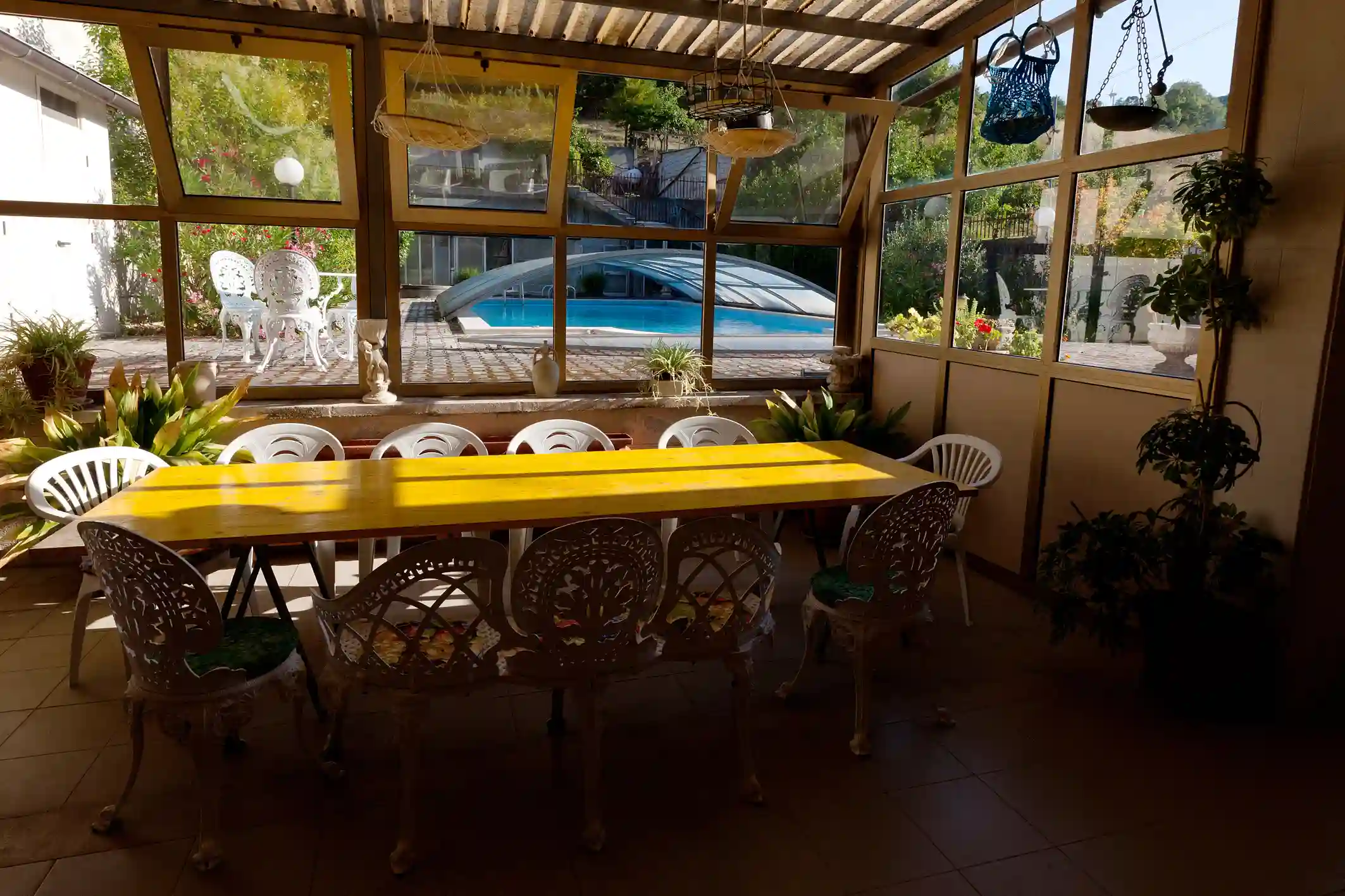Long shared table in the conservatory at La Vita Sukha, looking out to the pool